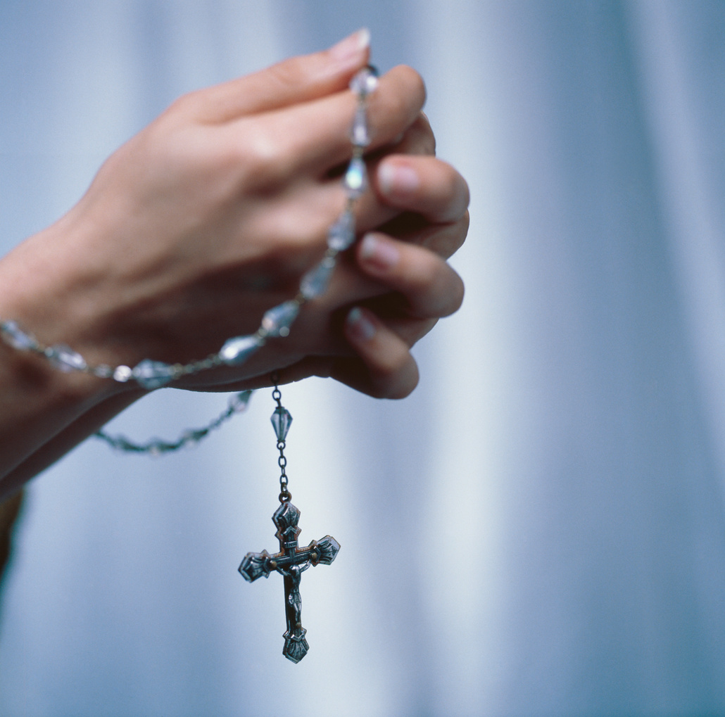 Close-up of a woman's hands praying with rosary beads